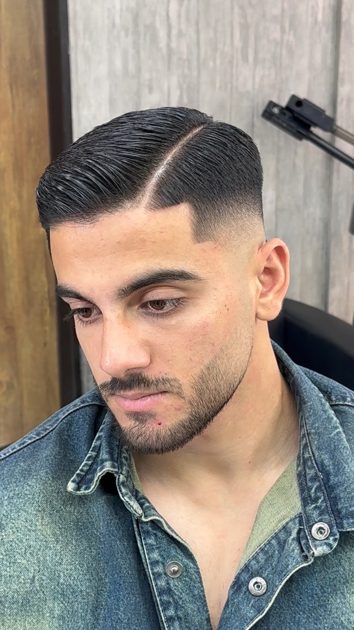 Man with a sharp side part haircut and high skin fade.