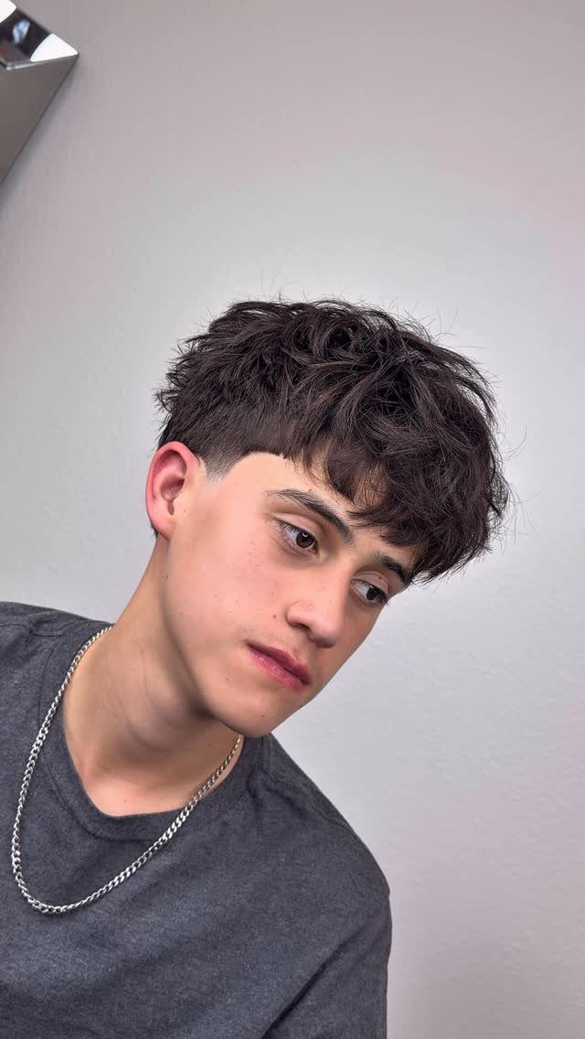 Young man with curly textured top and a clean taper fade haircut.