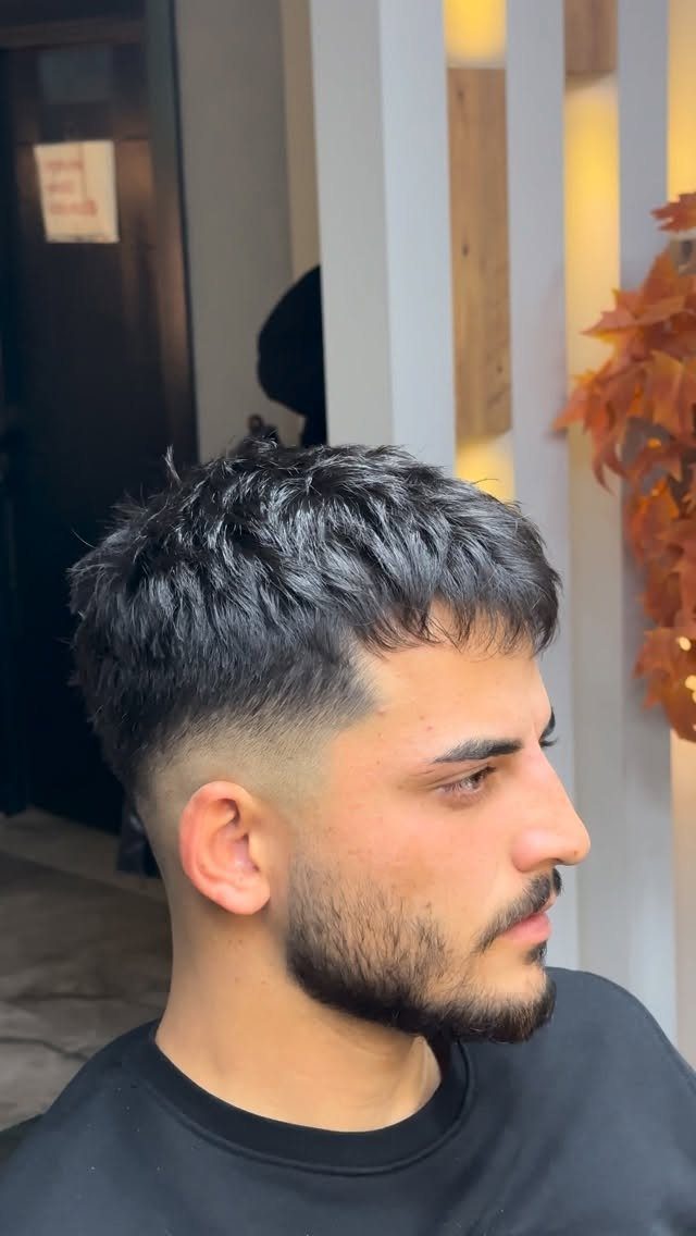 Man with a textured French crop haircut and high skin fade in profile.