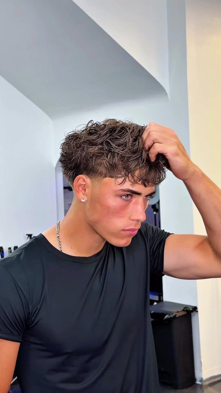 Young man with a textured fringe haircut and faded sides wearing a black shirt.