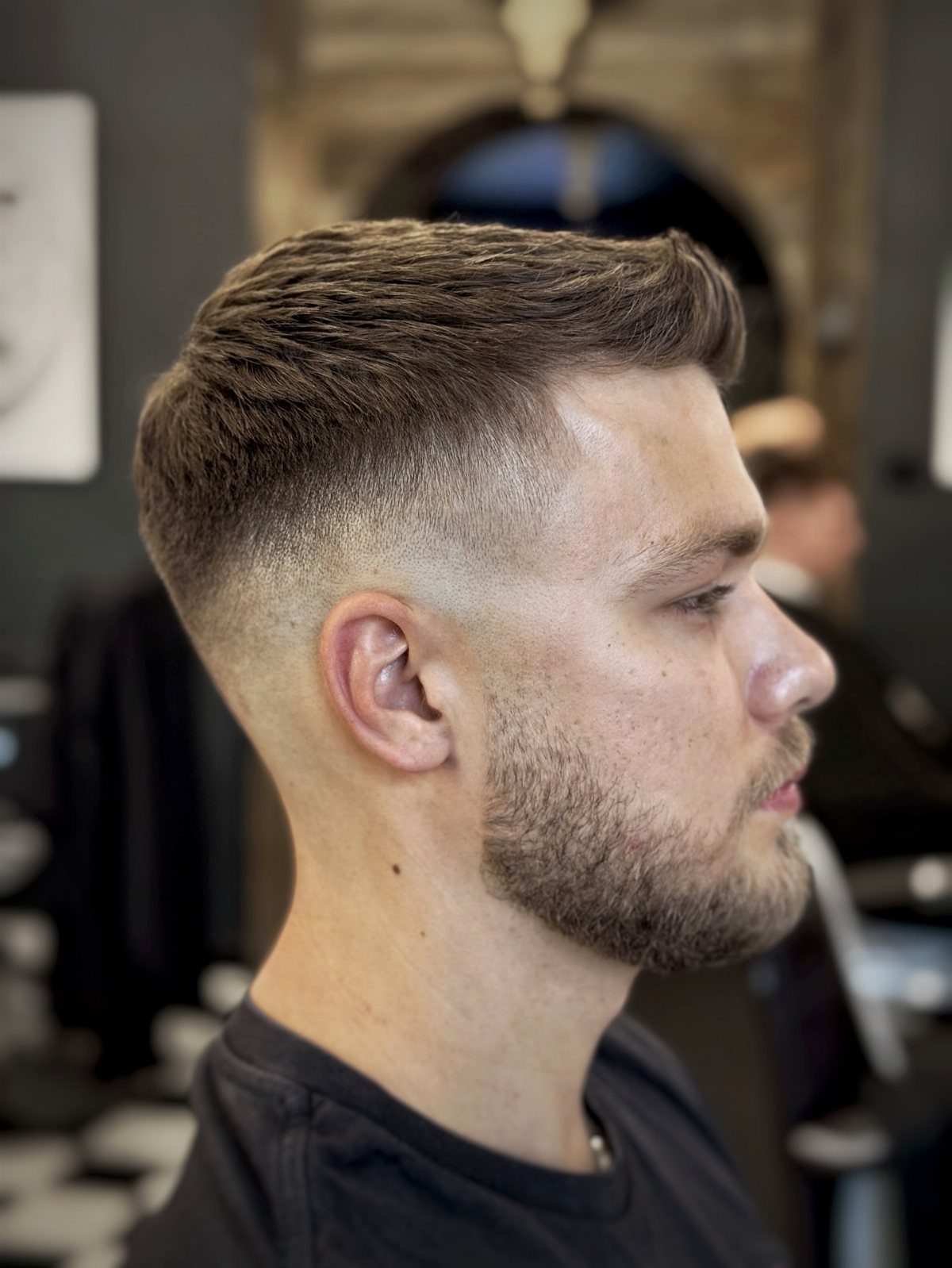 Man with a textured quiff haircut and high skin fade in a barbershop.