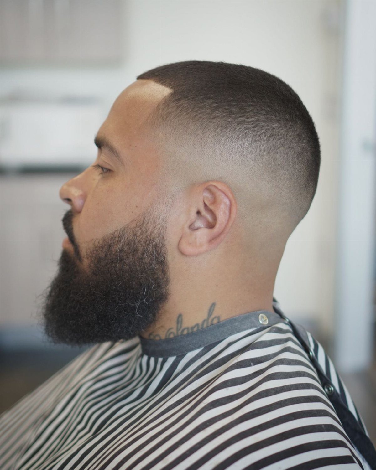 Man with a bald mid fade haircut and a thick dark beard.