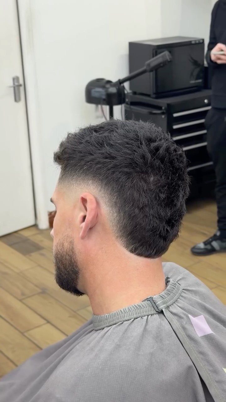 Man with a burst fade haircut showing the rounded fade around the ear.