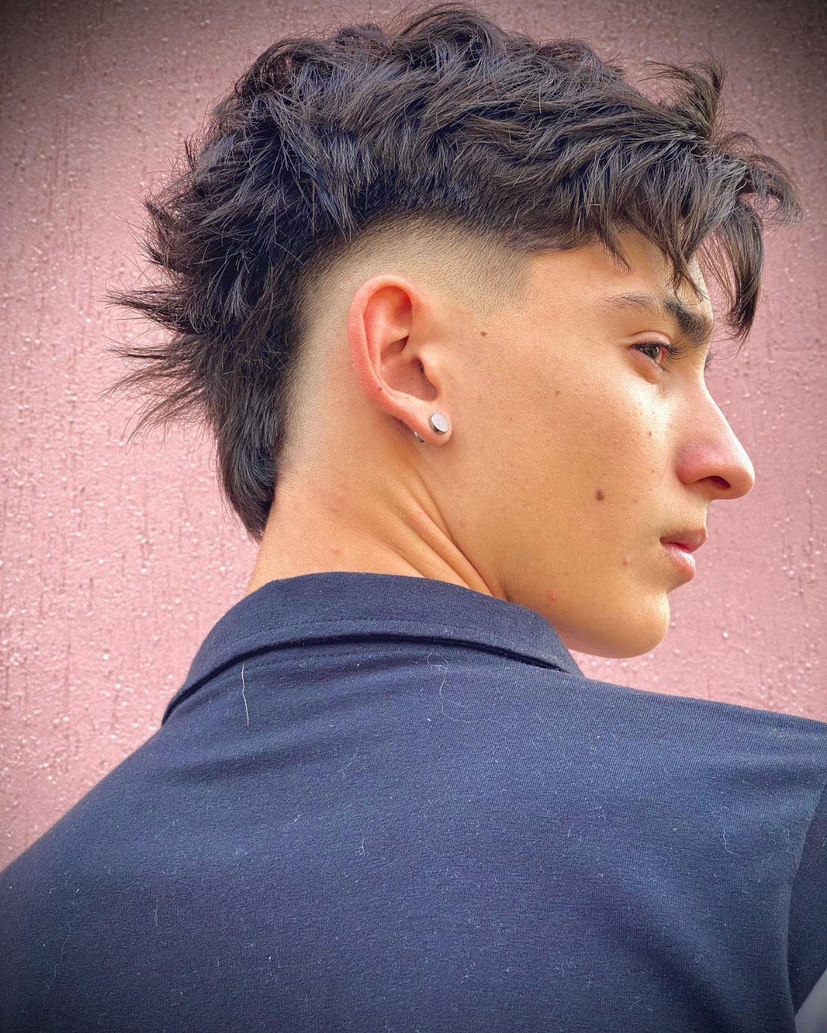 Young man with a faded mohawk haircut and textured dark hair.