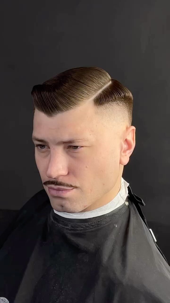 Man with a brown hard part fade haircut and a groomed mustache.