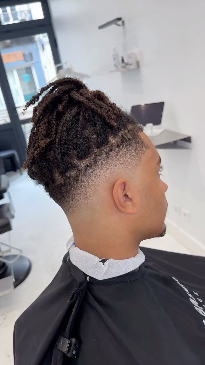 Man with short dreadlocks and a clean mid fade haircut in a barbershop