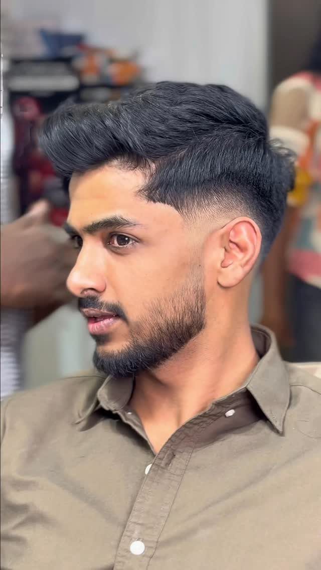 Man with a mid fade haircut and groomed beard wearing a brown shirt.