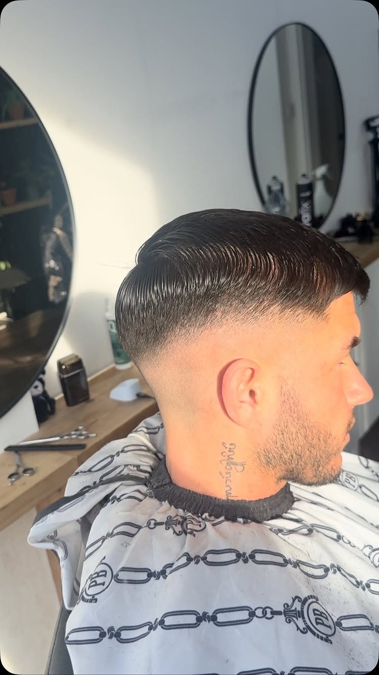 Man with a skin fade haircut and groomed beard in a barbershop setting.
