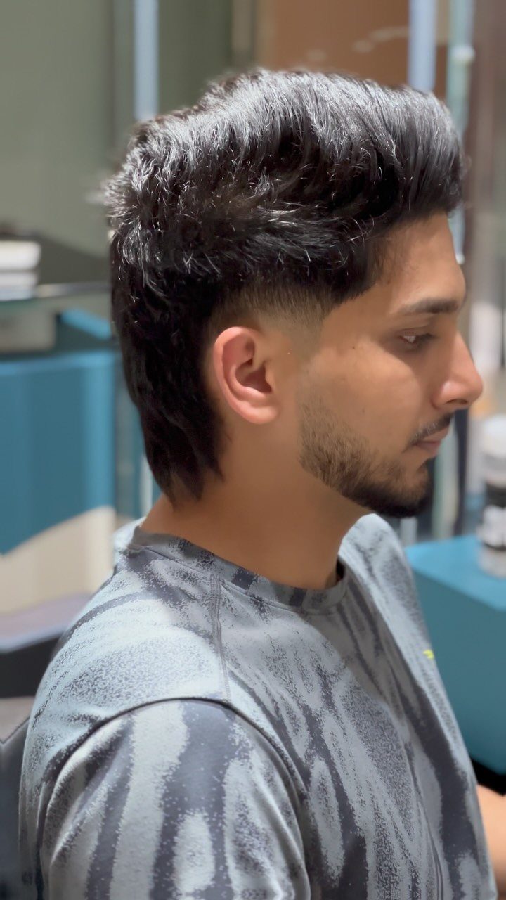 Man with a taper fade haircut and voluminous dark hair on top.