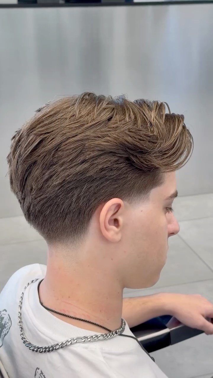 Young man with light brown hair featuring a clean taper haircut and styled top.