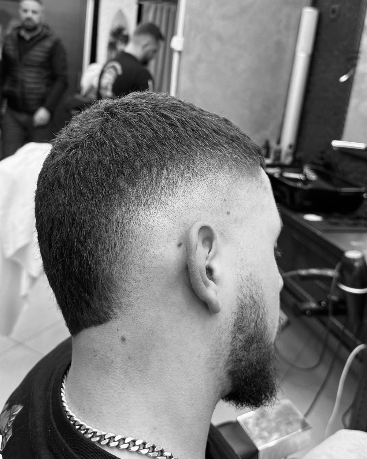 Man with a burst fade haircut and groomed beard in a barbershop setting.