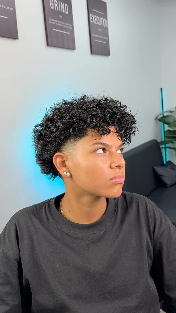 Person with curly black hair and a fade haircut wearing a black t-shirt.