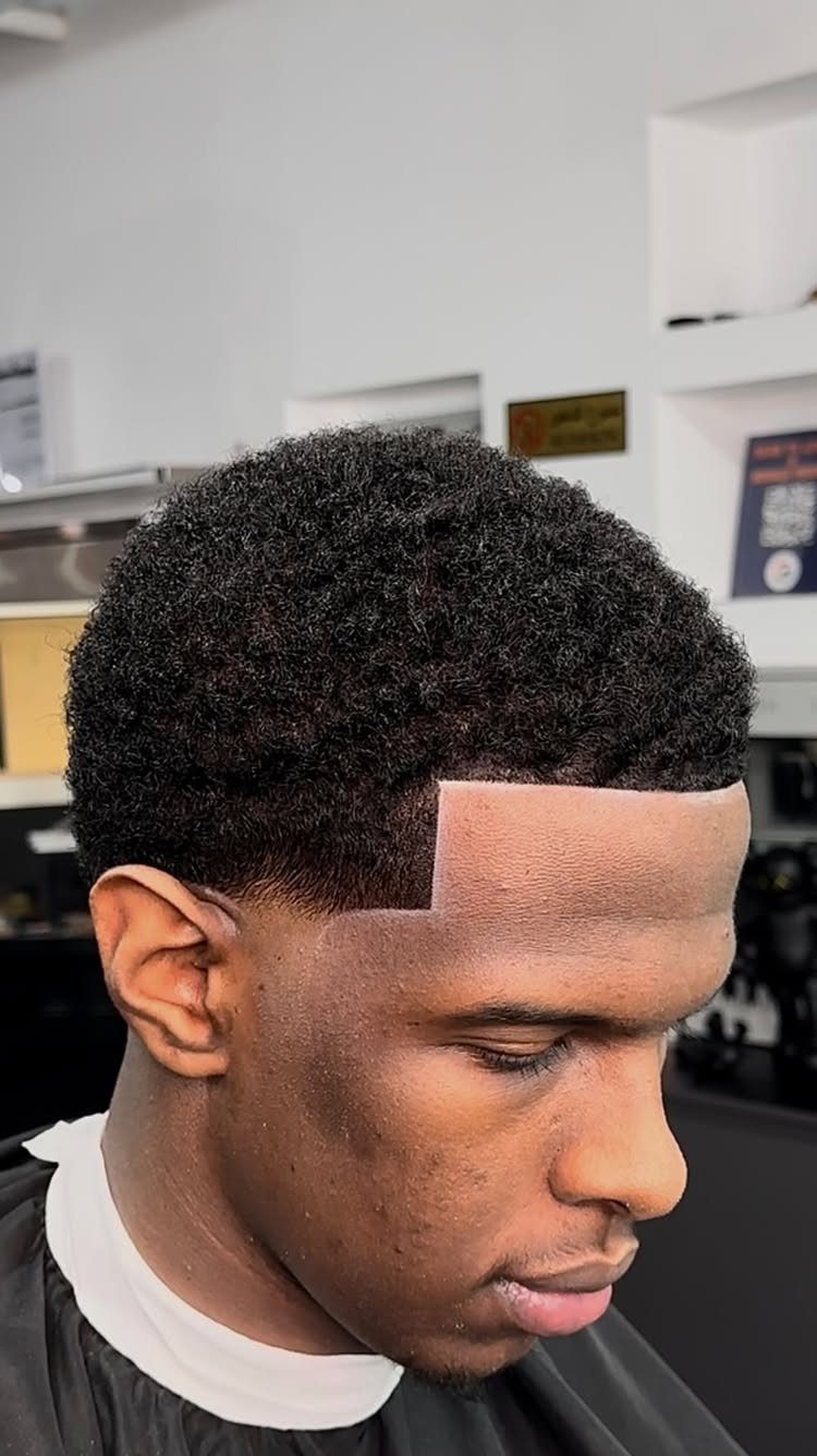 Man with a short curly afro and a clean fade haircut in a barbershop