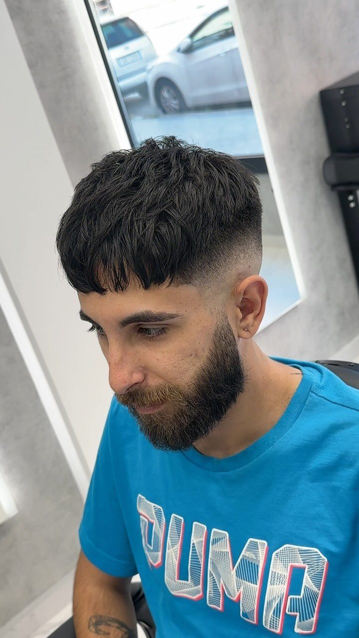 Man with a French crop haircut featuring a textured top and high skin fade.