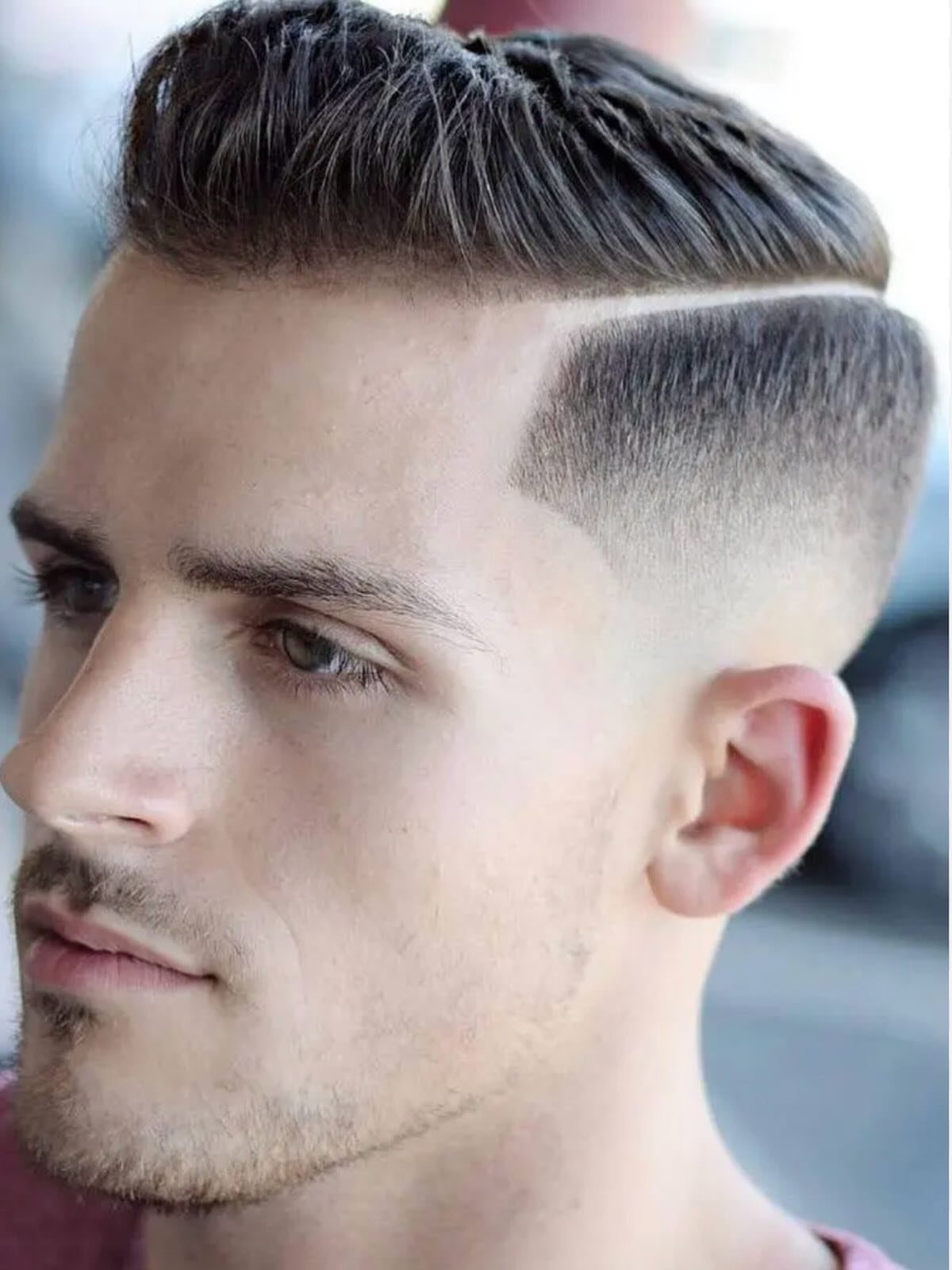 Man with a mid fade haircut and a sharp shaved hard part line.