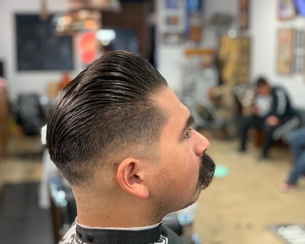Man with a slicked-back pompadour hairstyle and fade in a barbershop setting