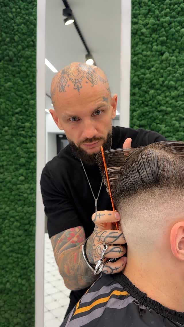 Barber styling a man's side part haircut with a skin fade in a shop.
