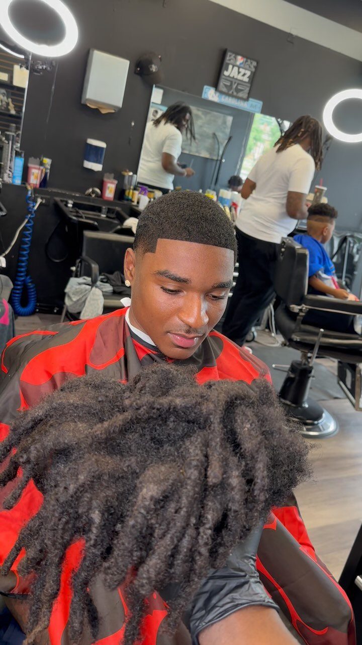 Man with a fresh taper fade haircut wearing a red barber cape.
