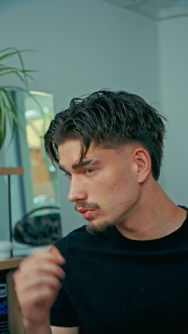 Young man with a dark wavy top and a clean fade haircut.