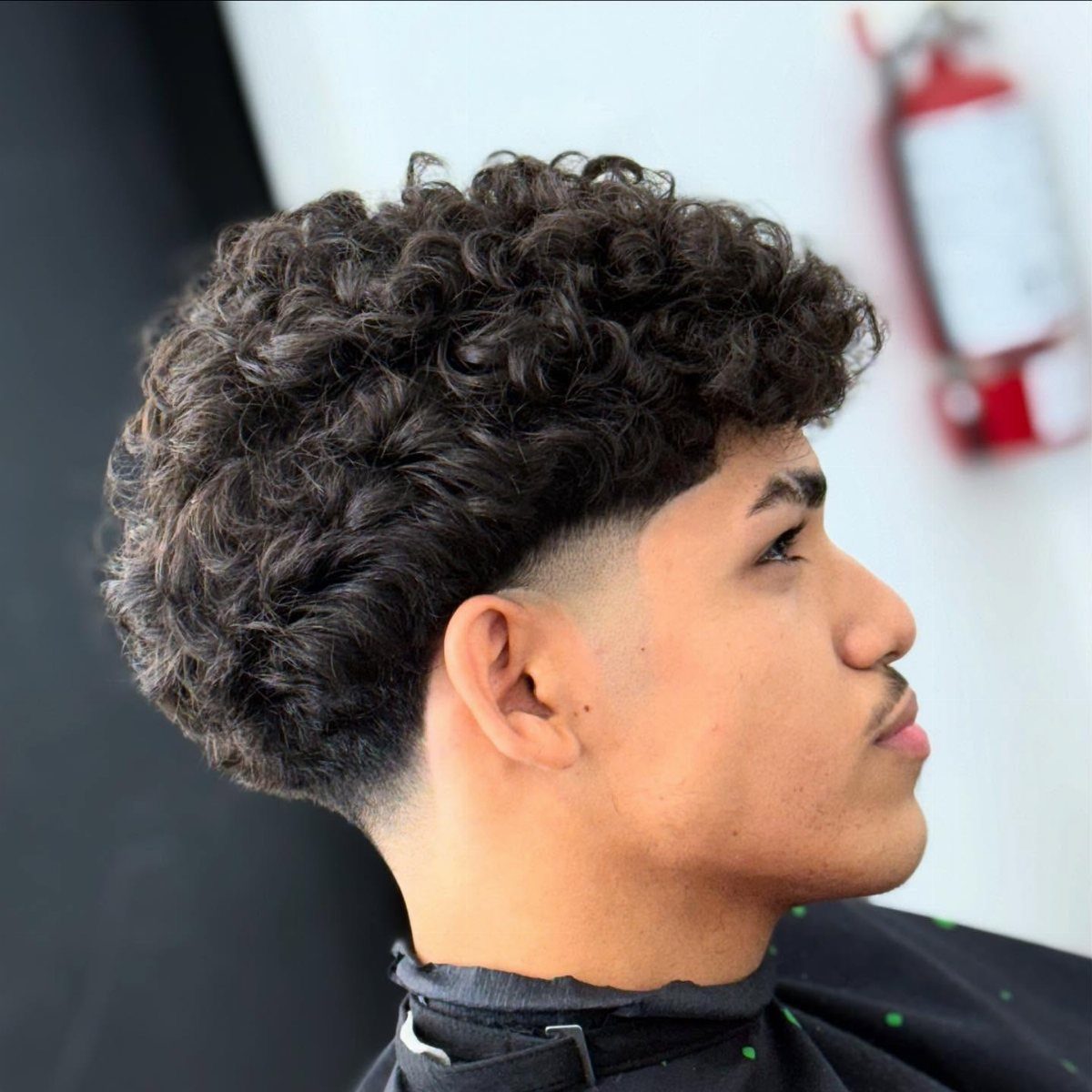 Young man with a curly broccoli haircut featuring faded sides and voluminous top.