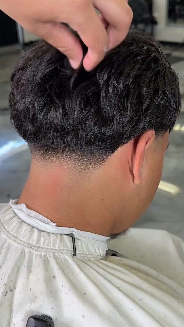 Man with a skin fade haircut and long textured dark hair on top.