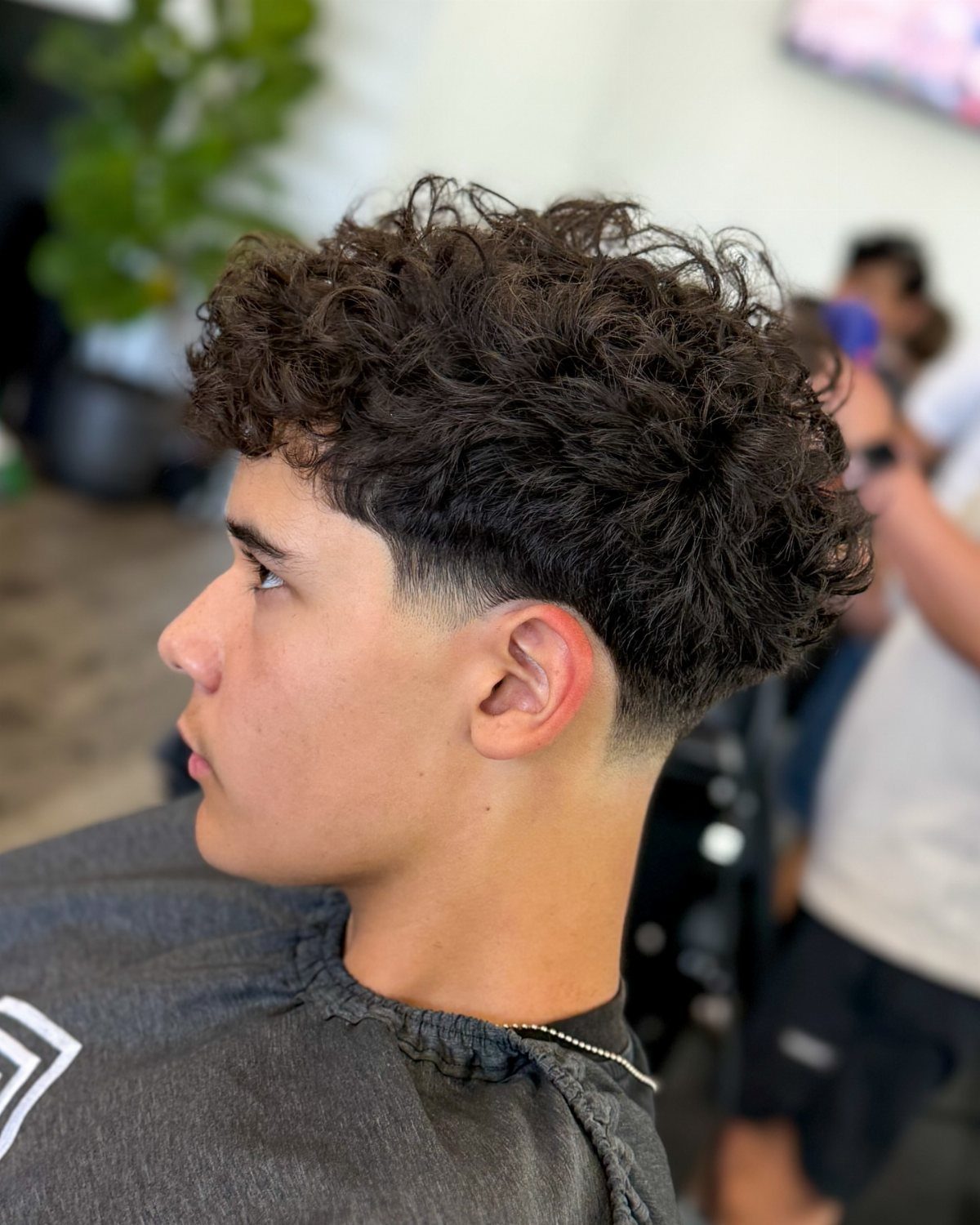 Young man with a curly top haircut and a high skin fade.
