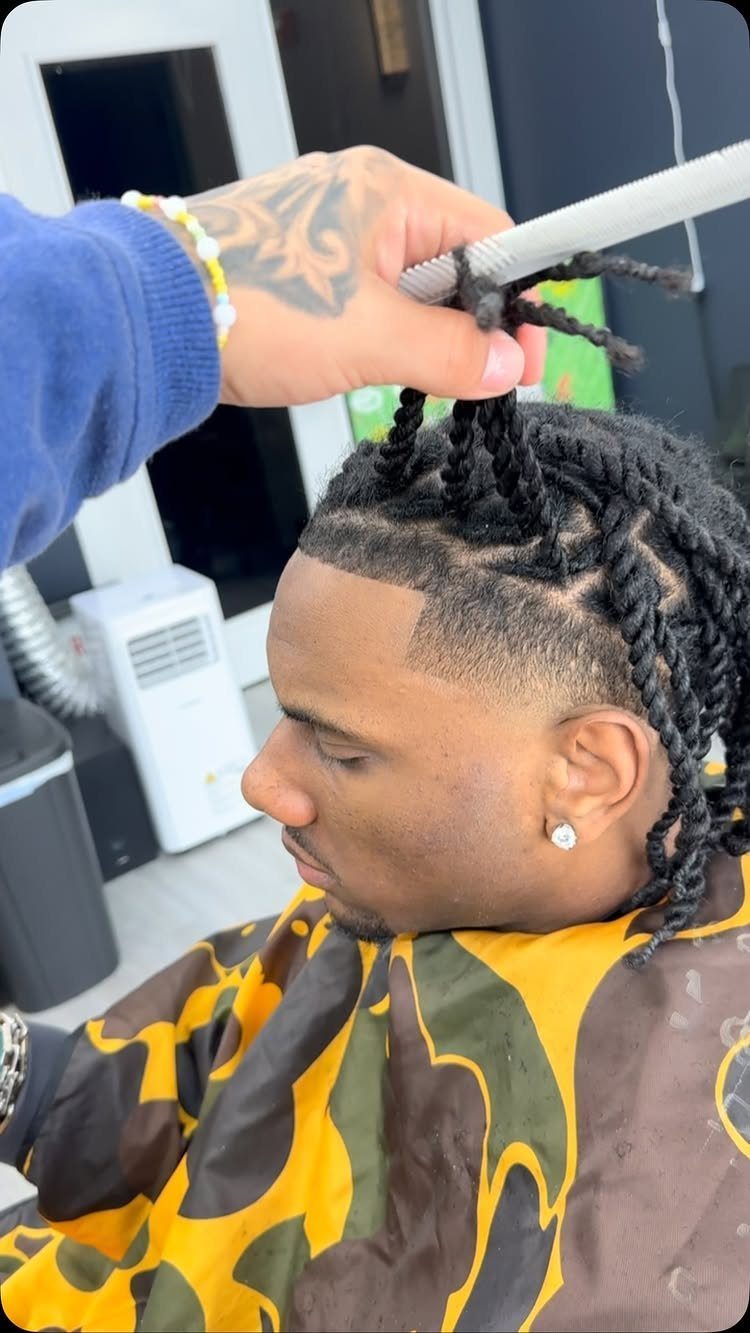 Man with black hair twists and a side fade in a barbershop