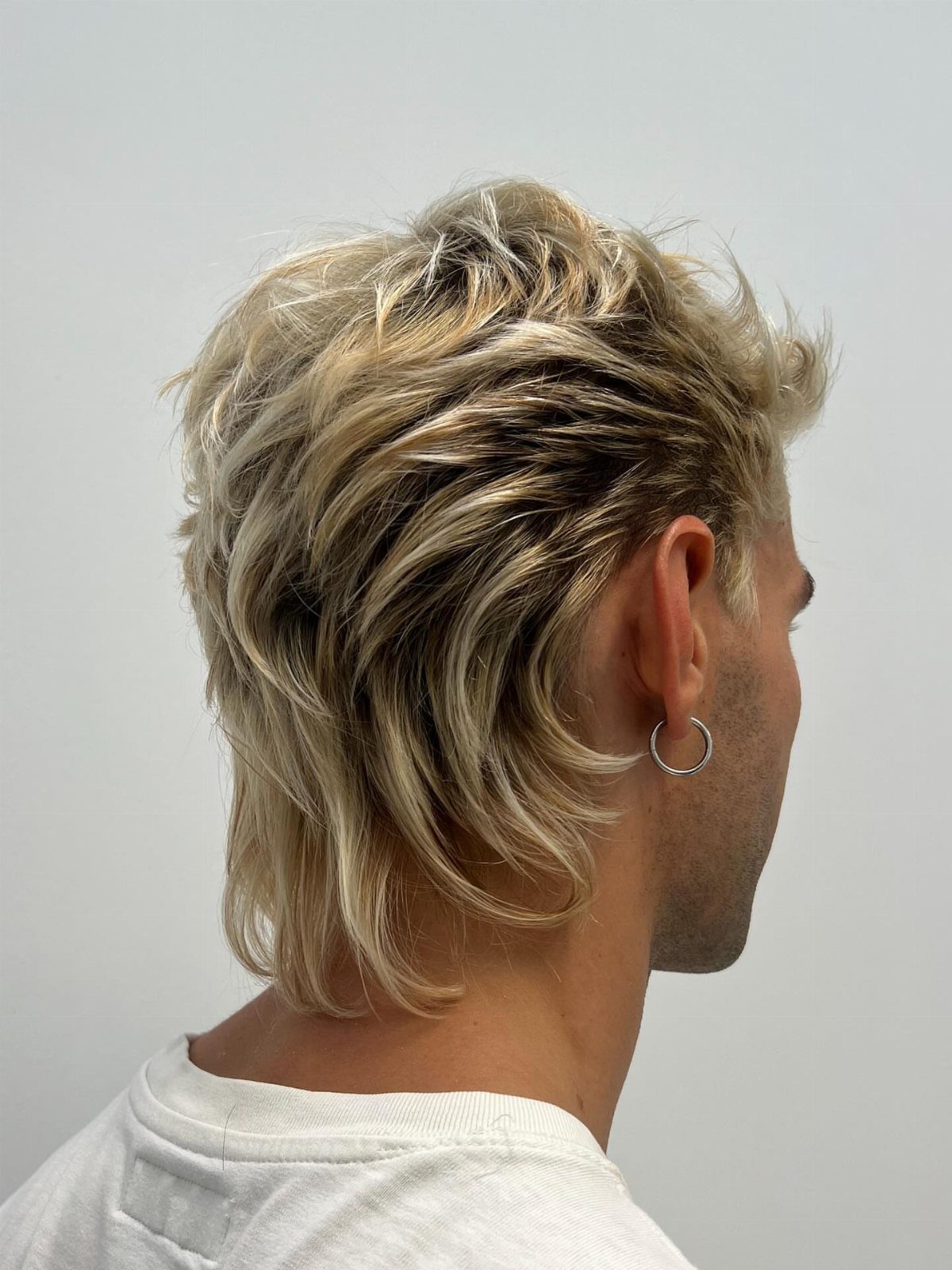 Man with medium length wavy blonde hair in a modern shag haircut style.