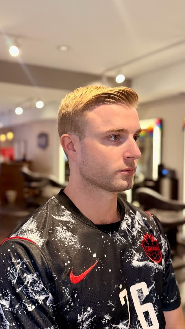 Young man with blonde hair styled in a side part wearing a sports jersey.