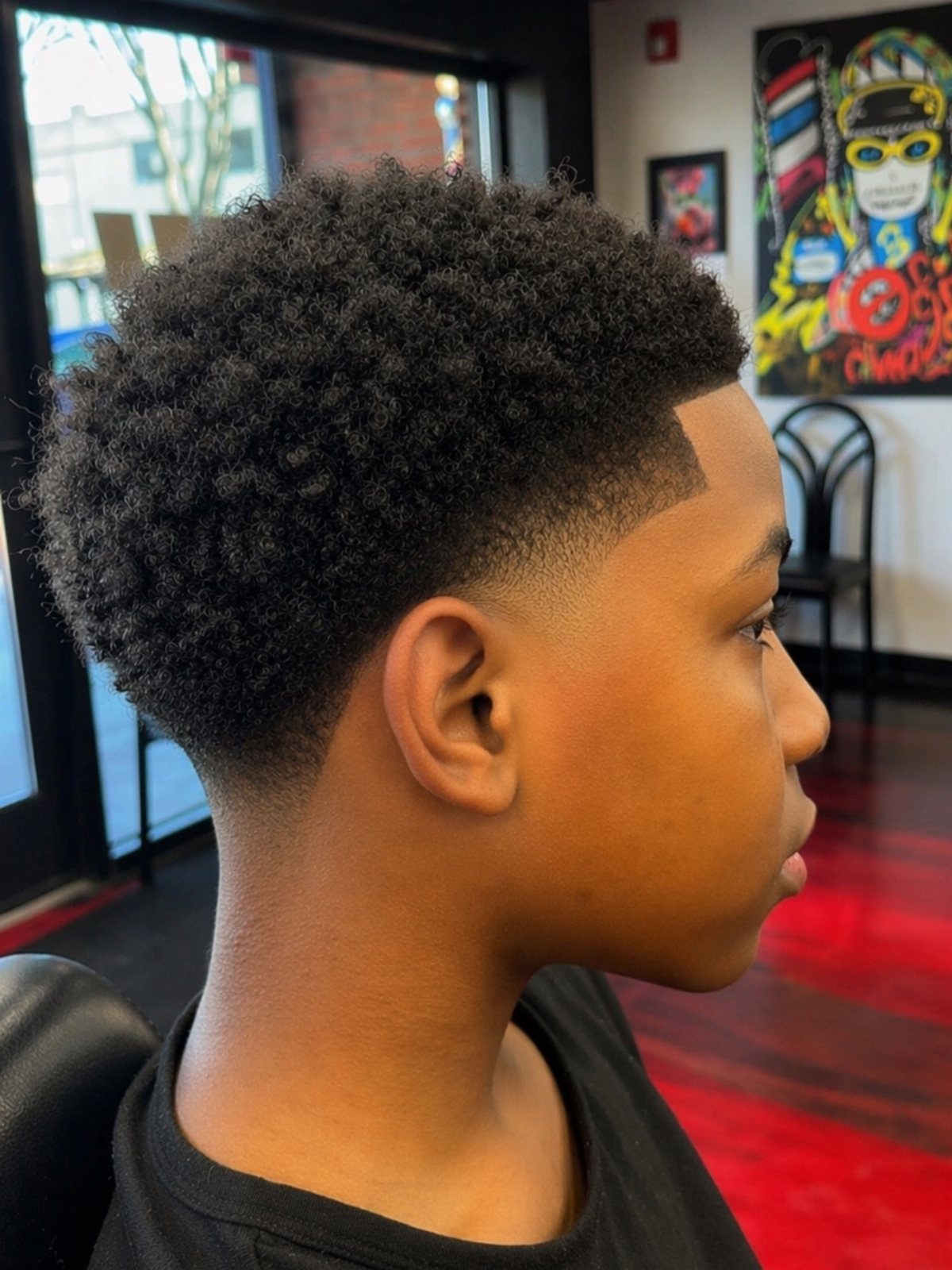 Young man with a short natural Afro and a clean taper fade haircut.