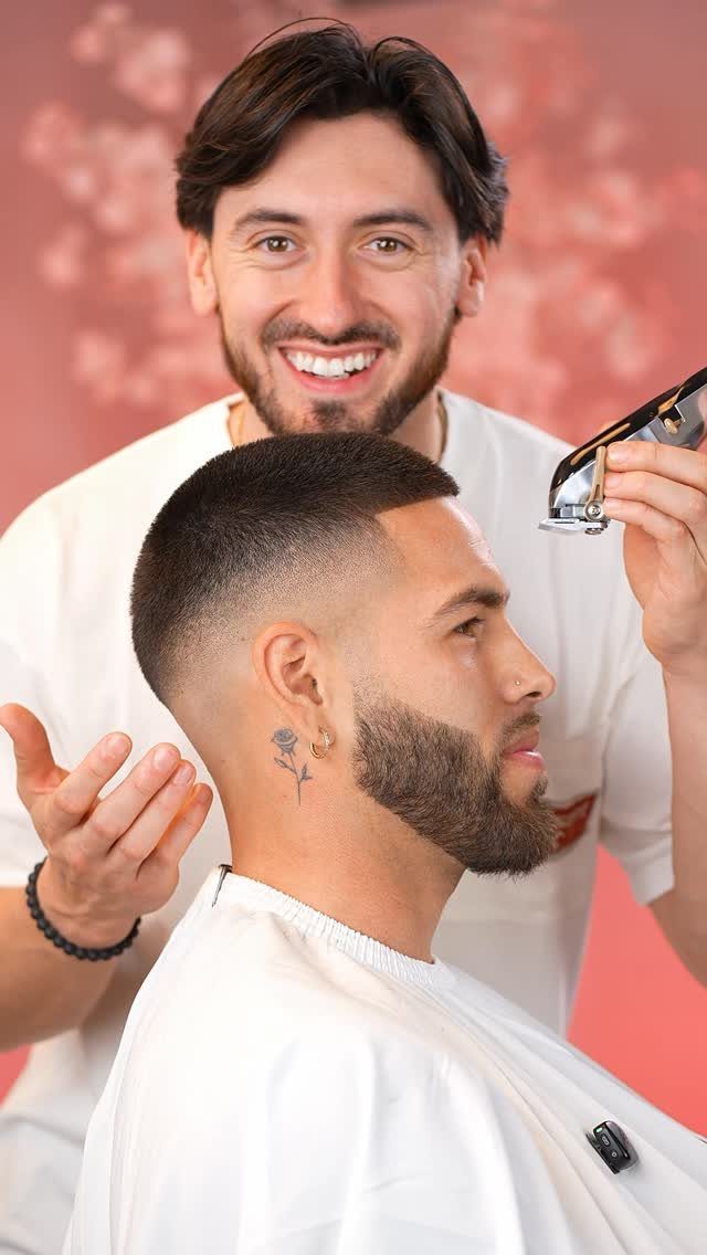 Man with a drop fade haircut and beard being shown his hair by a barber.