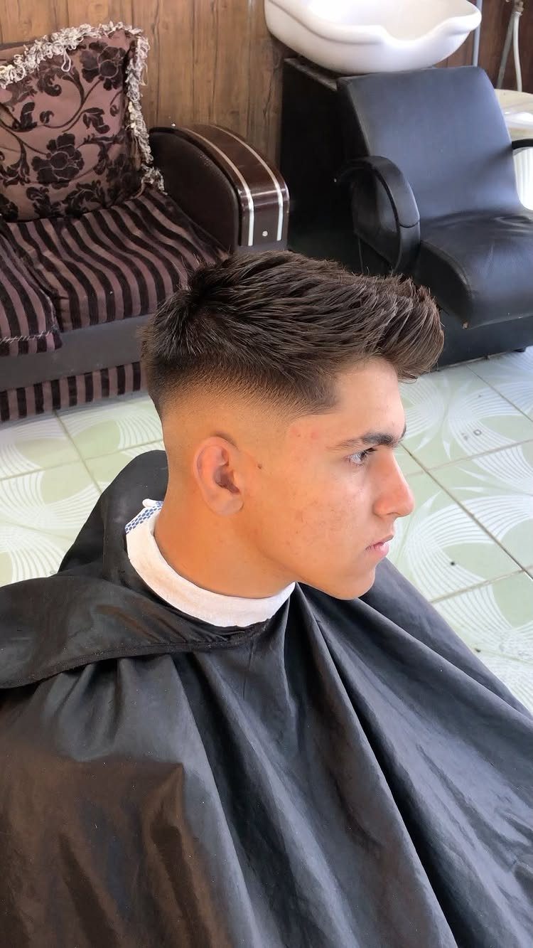 Young man with a high fade haircut and textured top in a barbershop