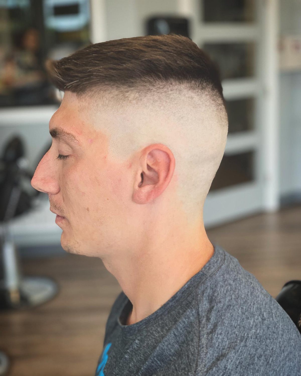 Man with a high and tight fade haircut and styled short top.