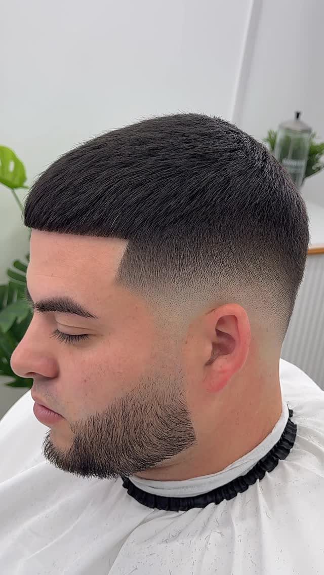 Man with a short dark haircut featuring a mid fade and straight fringe.