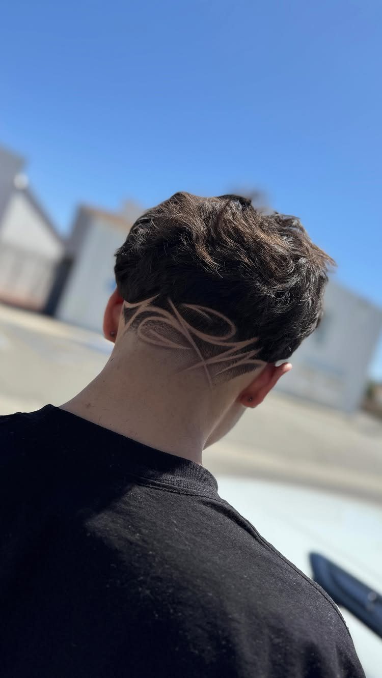 Man with short brown hair and a shaved curved design on his neck.