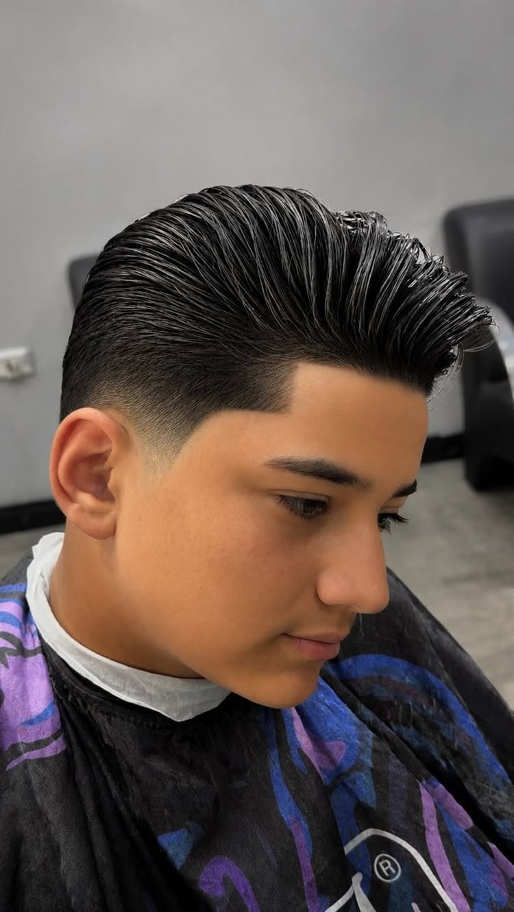 Young man with a voluminous pompadour haircut and a clean skin fade.