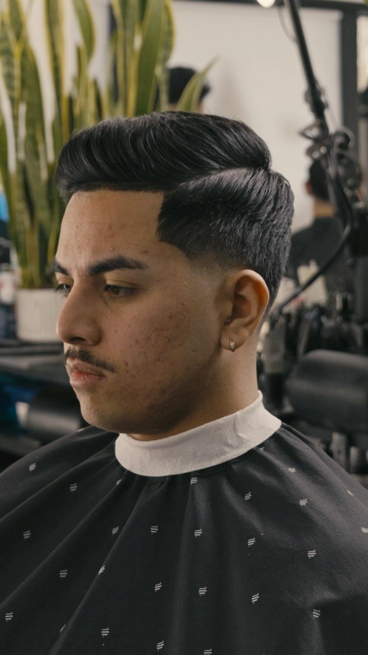 Man with a side part haircut and fade in a barbershop setting