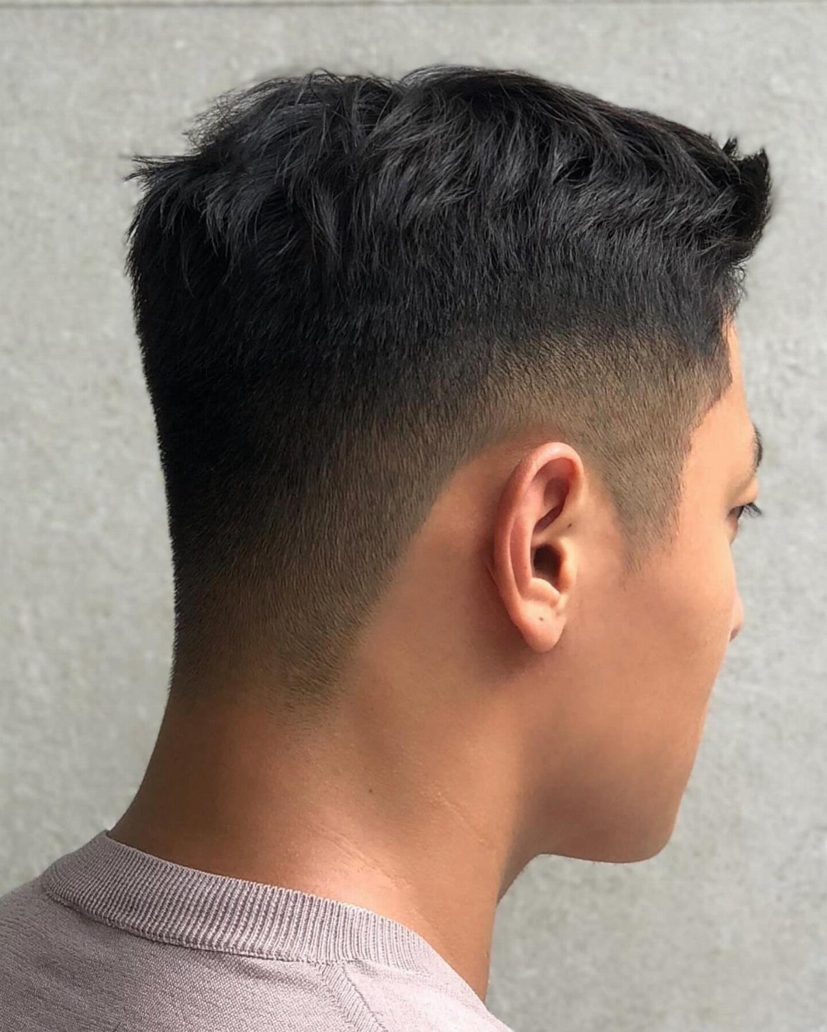 Man with a high skin fade and textured short dark hair on top.