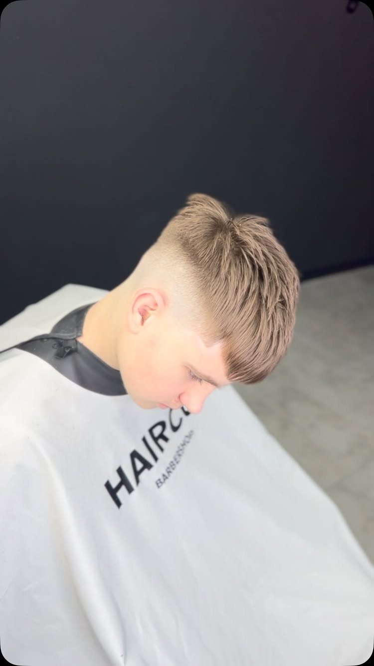 Young man with a textured crop haircut and high skin fade in a barbershop.