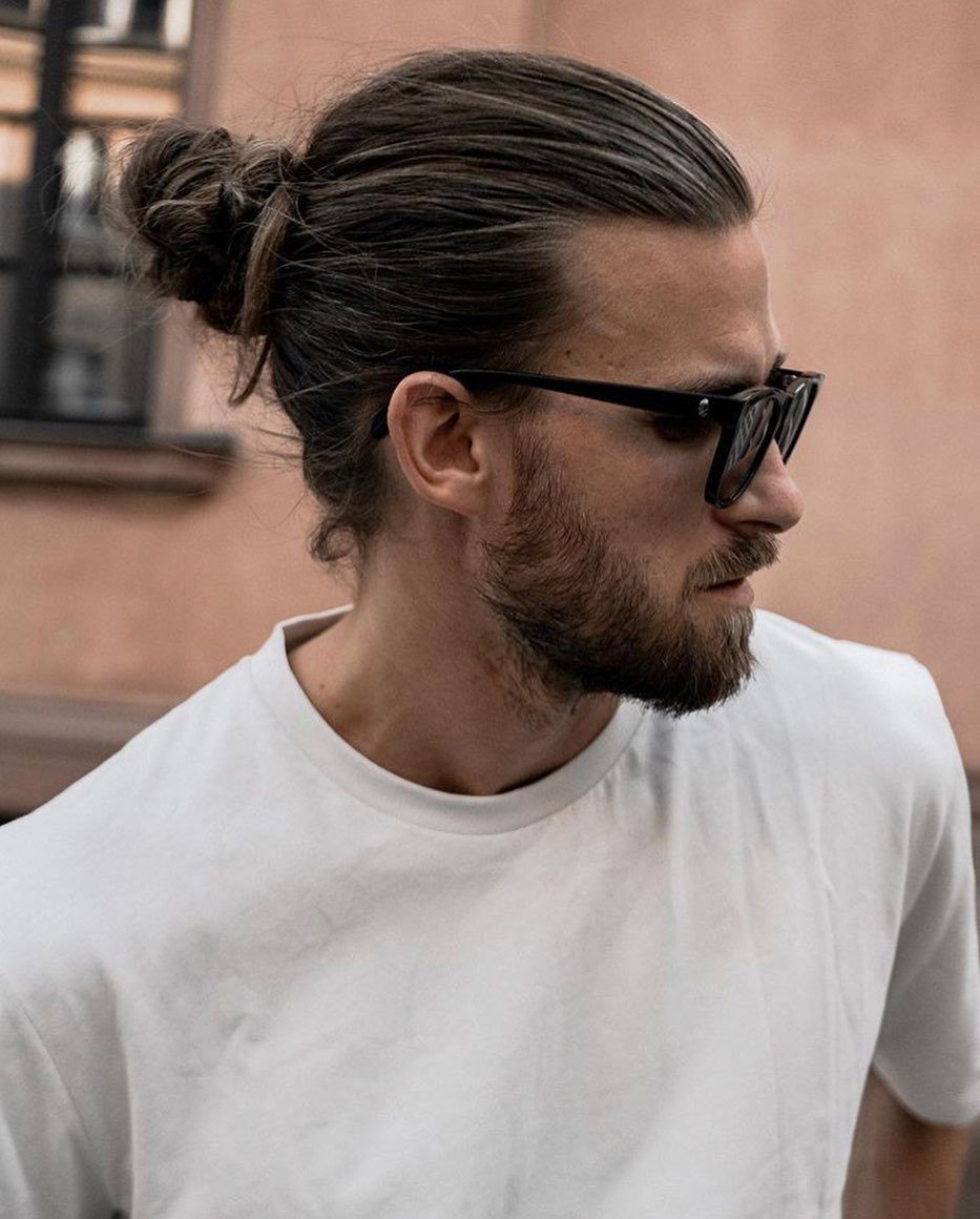 Man with a beard and sunglasses wearing his hair in a man bun.