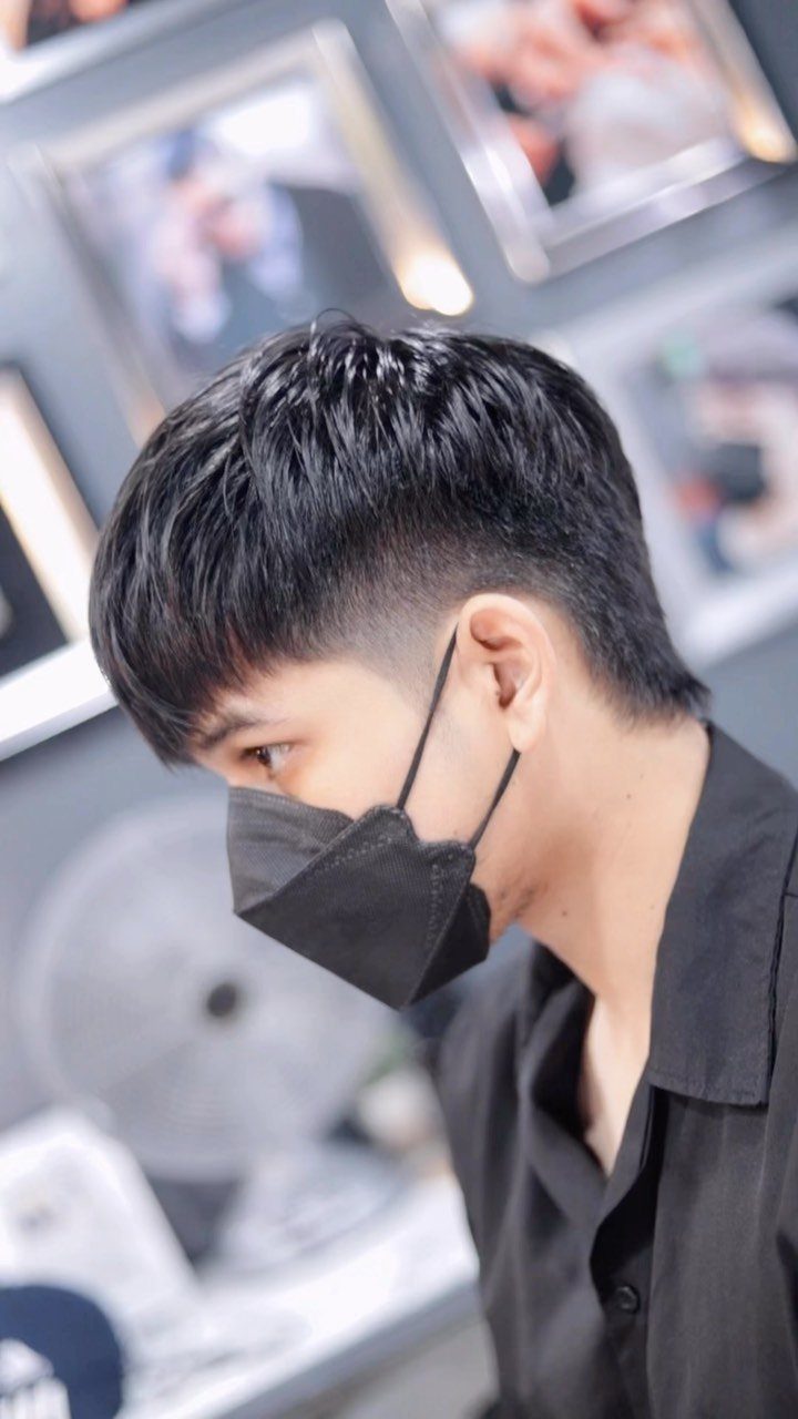 Man with a black mullet hairstyle wearing a black face mask and shirt.
