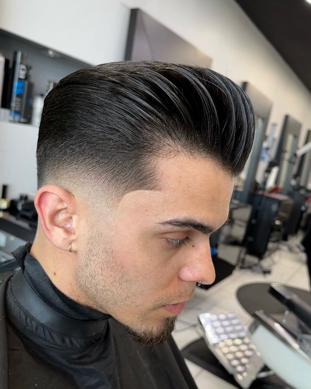 Man with a high volume pompadour hairstyle and a clean skin fade.