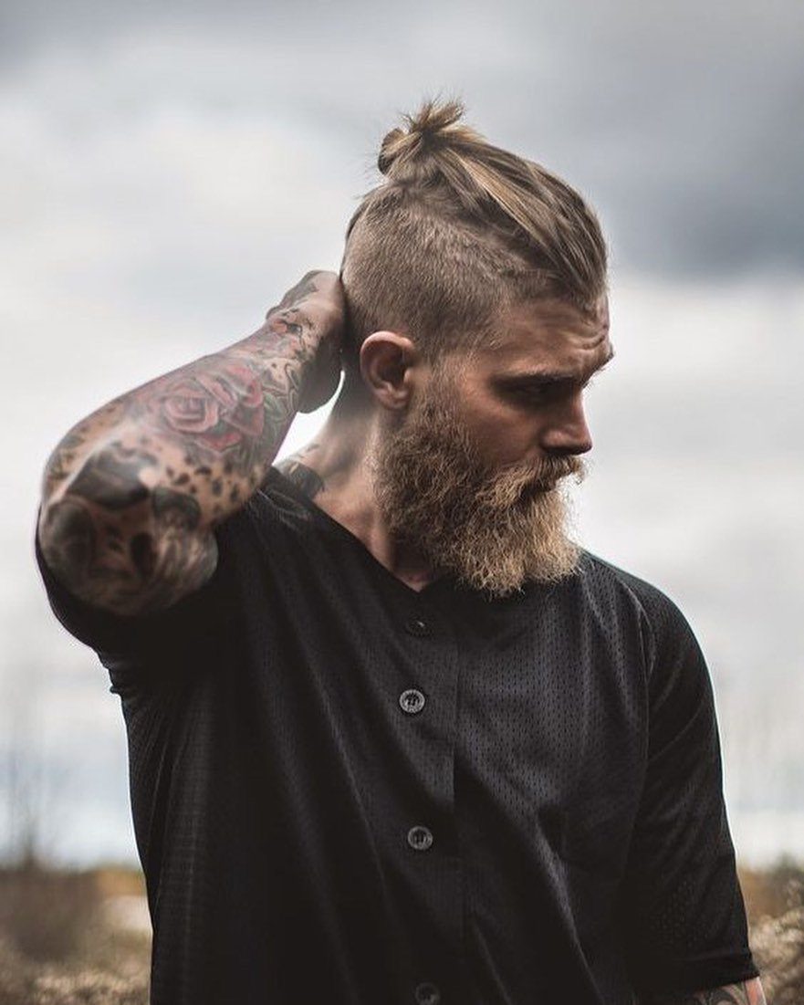 Man with a blonde beard and a textured topknot bun with shaved sides.