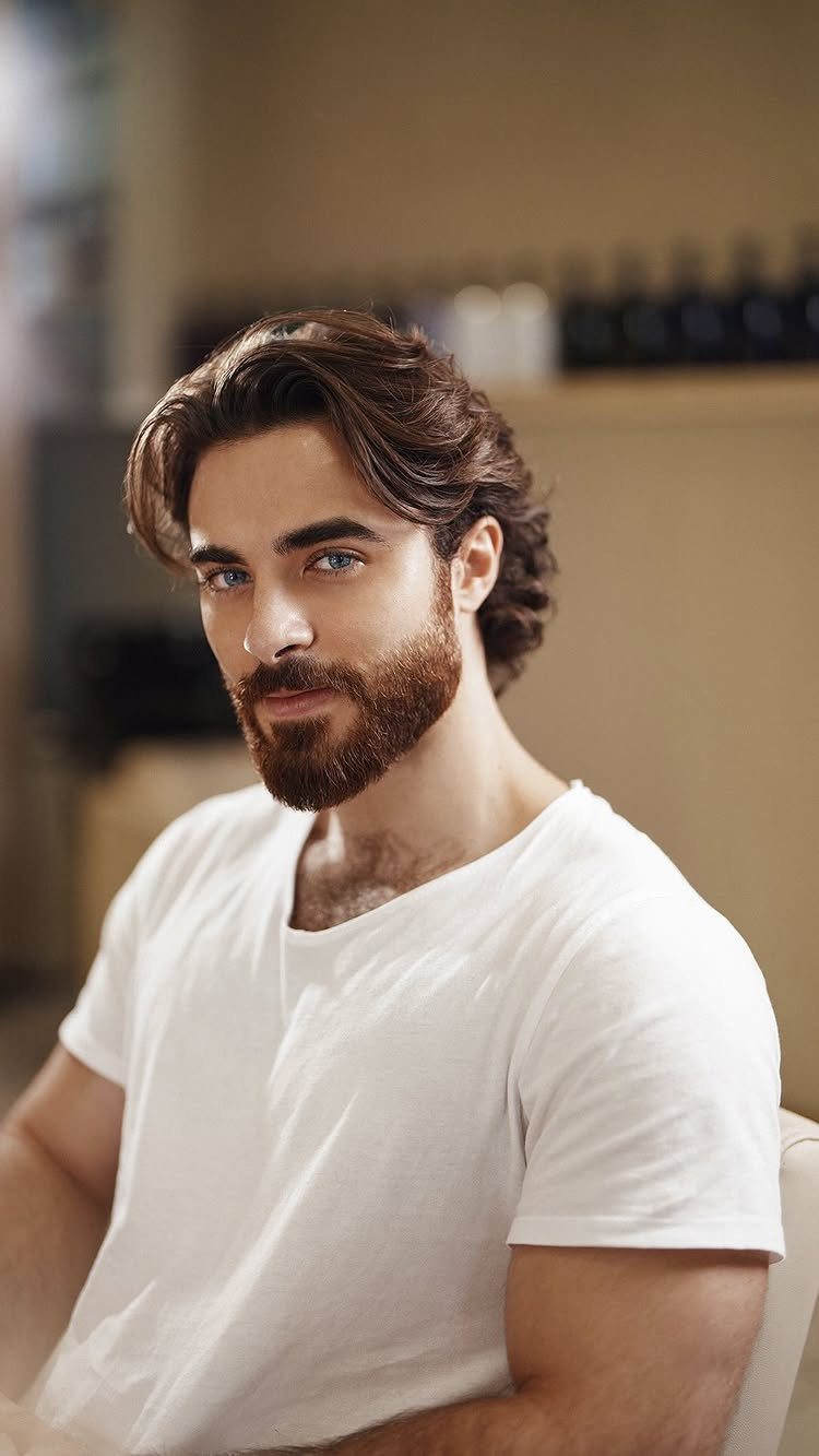 Man with brown medium-length hair swept back and a full groomed beard.