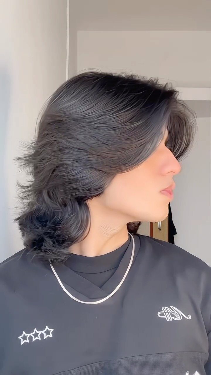 Man with long dark layered hair flowing to the shoulders in a side profile.
