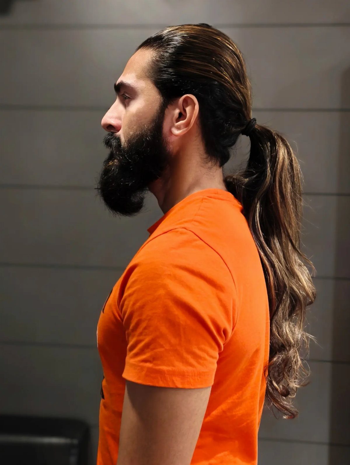 Man with a full beard and long brown hair tied in a low ponytail.