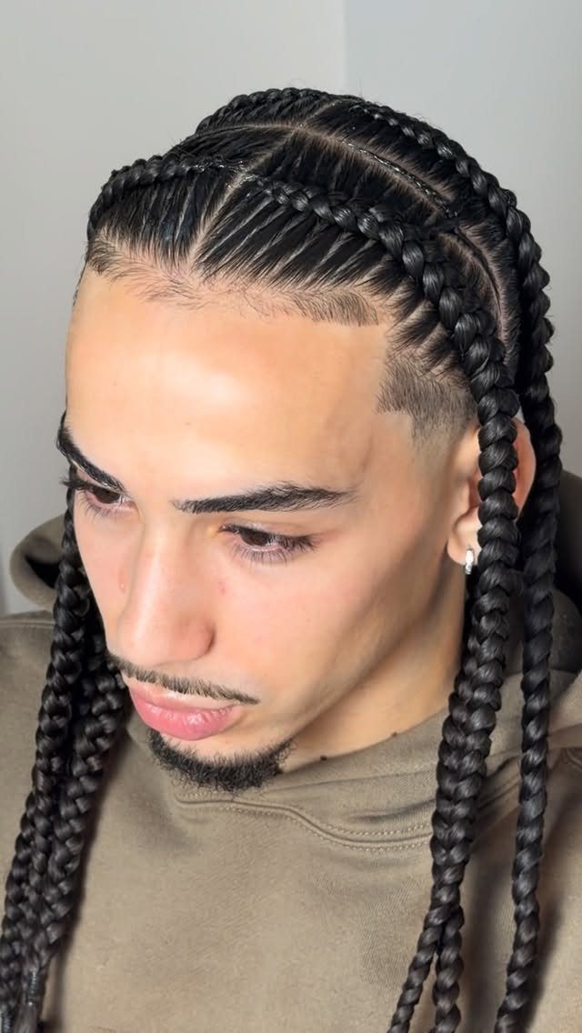 Man with dark hair styled in cornrow braids and long hanging braids.