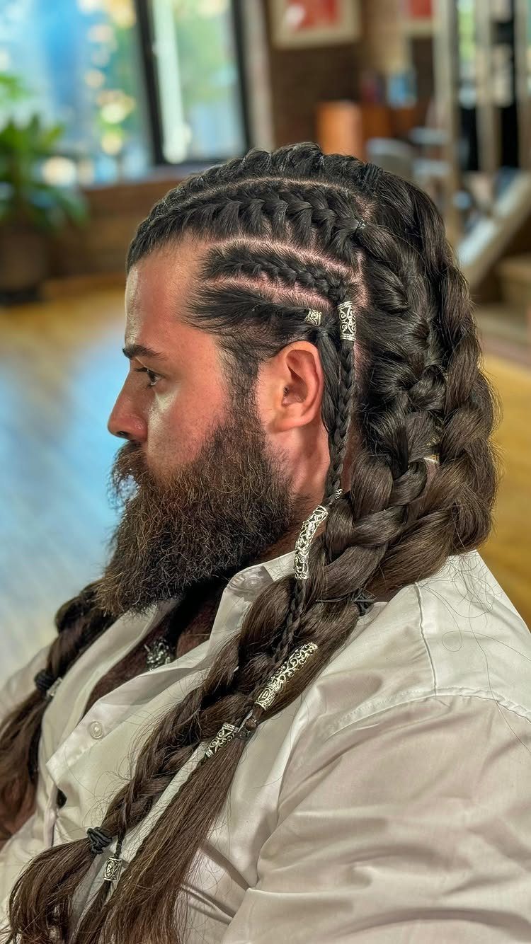 Man with a full beard and long brown hair styled in intricate braids.