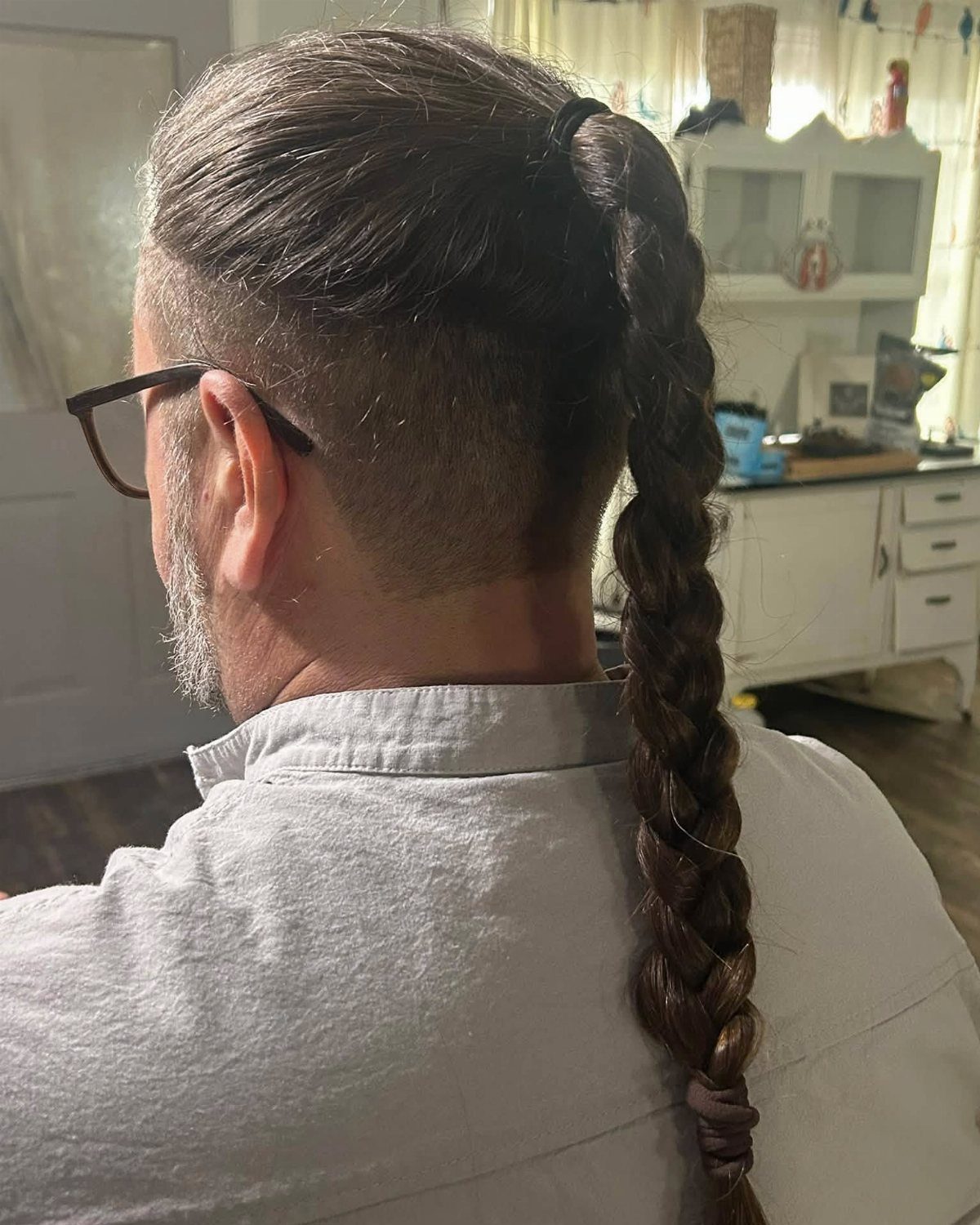 Man with a shaved side and a long brown braid tied back.