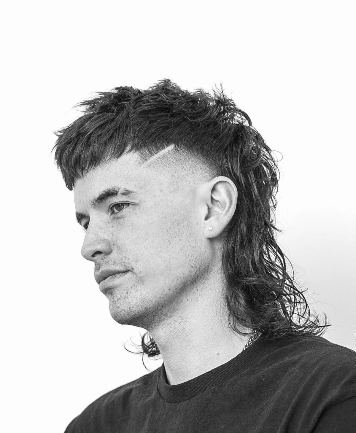 Man with a long mullet hairstyle and a shaved line on the side.